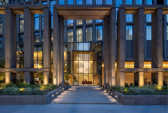 Front view of a modern building with tall pillars and large glass windows.