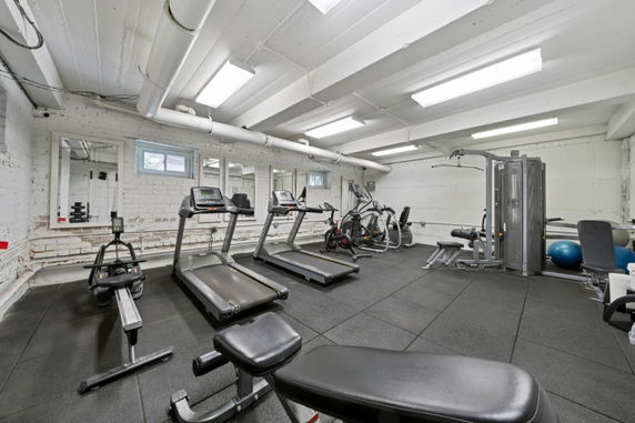 Indoor gym area with exercise equipment and mirrors on the wall.