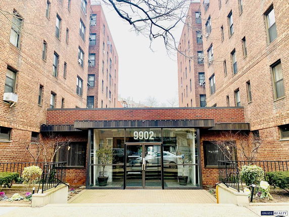 Front view of a multi-story brick apartment building with a glass entrance.