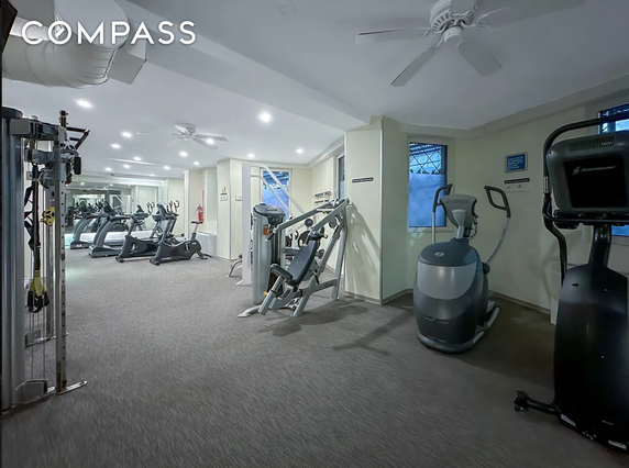Interior view of a gym area with exercise equipment and bright lighting.