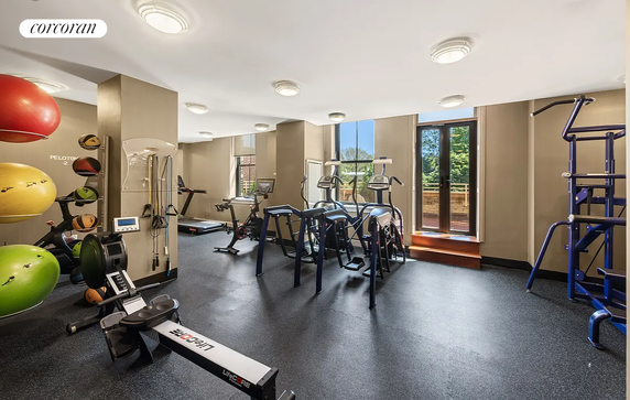 Indoor gym area with exercise equipment and large windows.