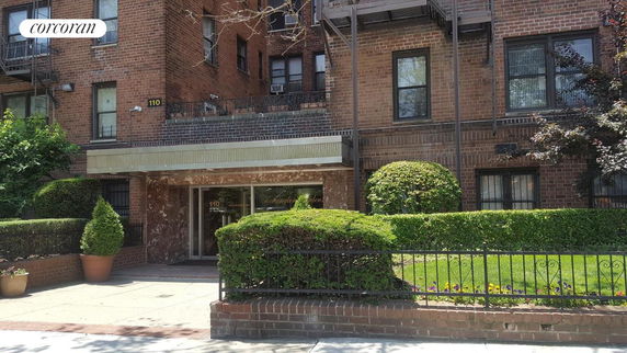 Front view of a brick apartment building with a covered entrance.