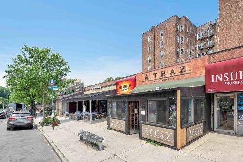 Street view of a row of commercial buildings with various shopfronts, including a café and insurance broker.
