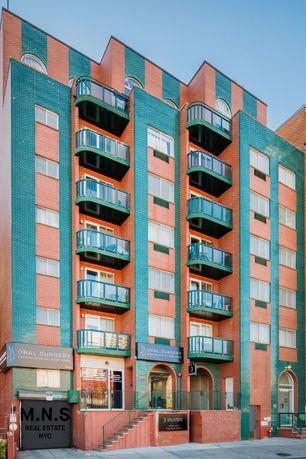 Front view of a multi-story brick building with green balconies.