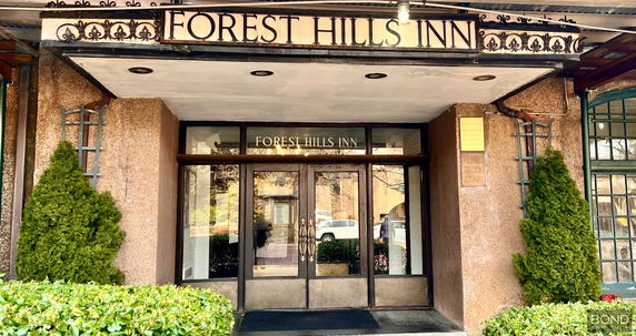 Front view of an inn entrance with glass doors and decorative signage.