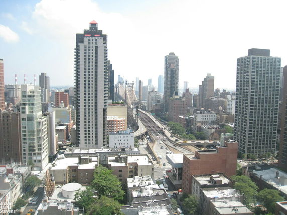 Panoramic view of a cityscape with multiple high-rise buildings and a nearby bridge.