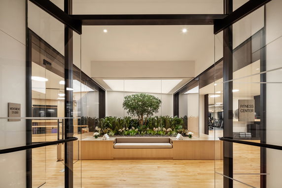 Interior view of a fitness center with glass doors and a central indoor garden.