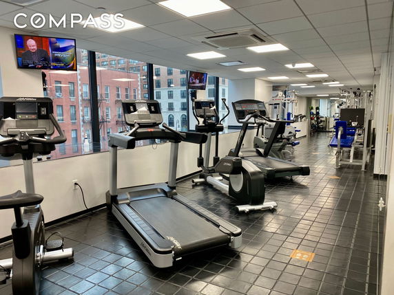Indoor gym with exercise equipment and large windows.