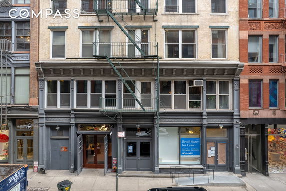 Front view of a multi-story building with retail spaces on the ground floor.