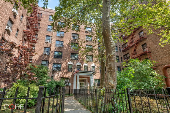 Front view of a multi-story brick apartment building with fire escapes.