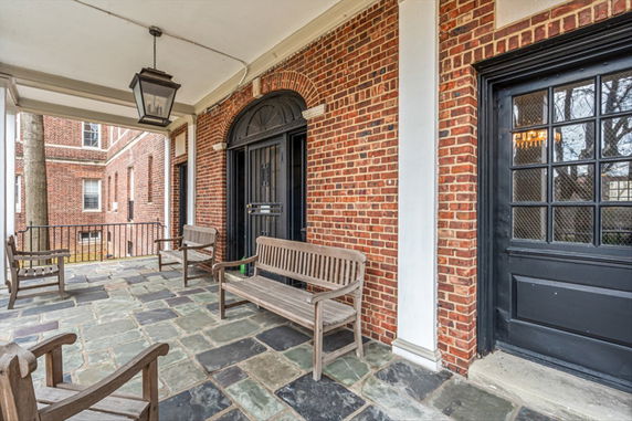 Front view of a building with a brick exterior and seating area on the porch.