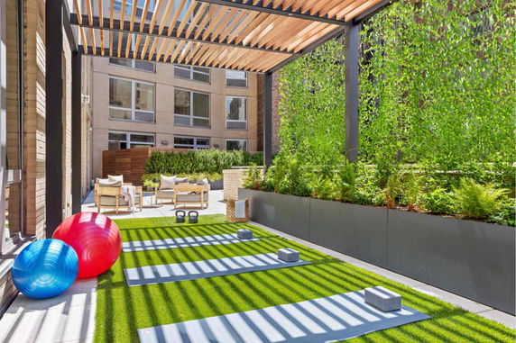 Outdoor fitness area with yoga mats, exercise balls, and plants.