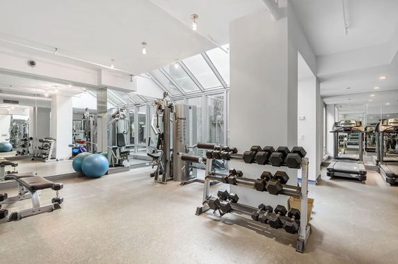 Indoor gym area with various exercise equipment including treadmills, dumbbells, and exercise machines.