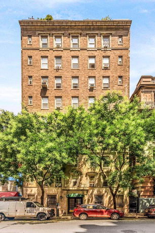 Front view of a multi-story brick building with multiple windows and a rooftop garden.