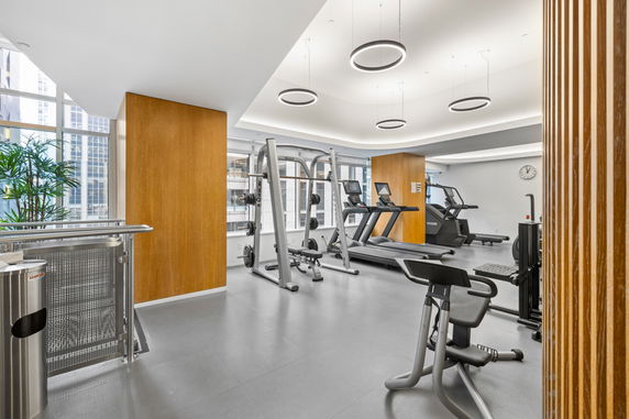 Interior view of a gym with exercise equipment and large windows.