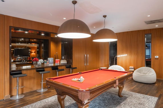 Room with a billiards table, bar stools, and lounge chairs.