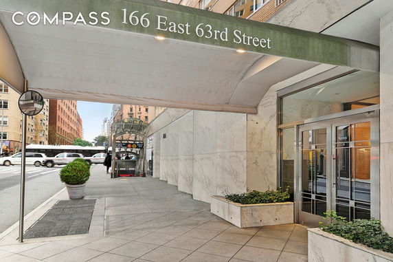 Entrance of a building with marble walls and a glass door, located at 166 East 63rd Street.