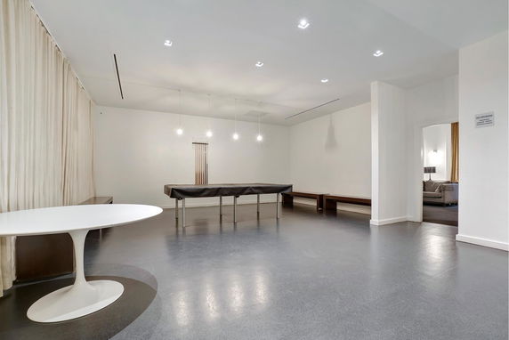 Interior space with a covered billiards table, modern lighting, and minimalist furnishings.