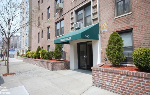 Front view of a brick apartment building with a green awning over the entrance.