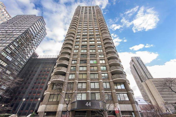 Front view of a tall residential building with multiple balconies.