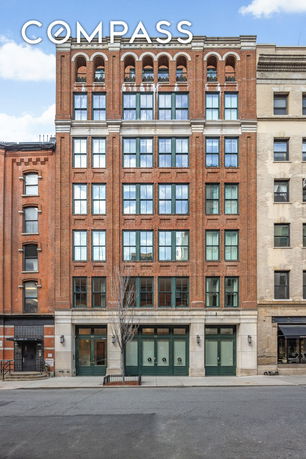 Front view of a multi-story brick building with large windows.