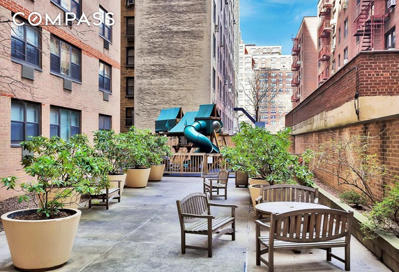 Outdoor area with planters and playground equipment between buildings.