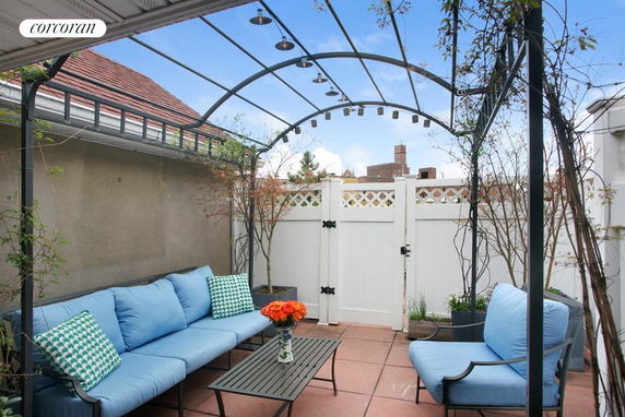 Rooftop seating area with a pergola and blue cushioned furniture.