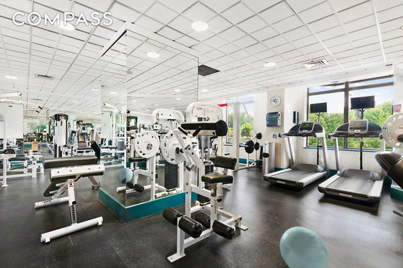 Interior view of a gym area with exercise equipment and mirrors.