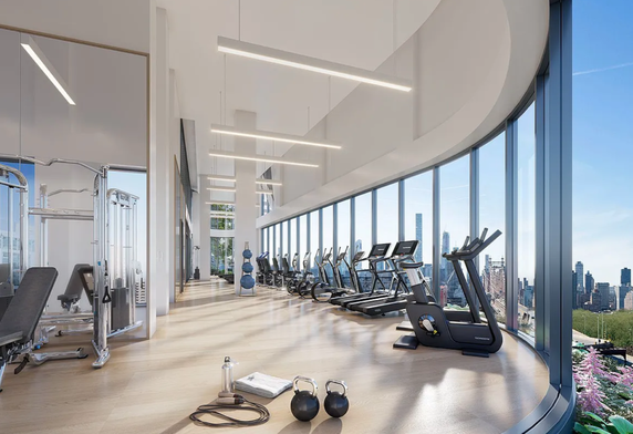 Modern gym area with exercise equipment and large windows revealing cityscape.