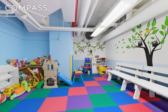 Indoor children's play area with colorful floor mats and various toys.