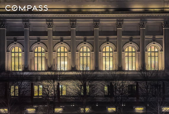 Front view of a building with illuminated arched windows and decorative columns.