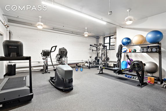 Indoor gym area with various exercise equipment and machines.