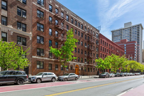 Front view of a multi-story brick apartment building with fire escapes.