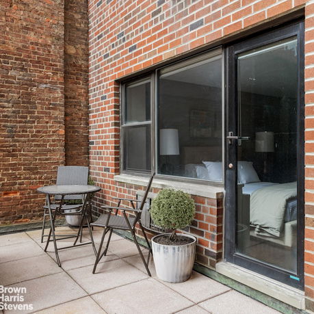 Rooftop patio area with brick walls, a small table, and chairs.