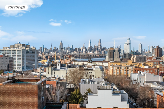 Wide angle view of a city skyline with various buildings and a bridge visible.