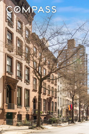 Street view of a row of multi-story townhouses with brownstone facades.