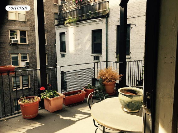 View from a balcony showing nearby apartment buildings with potted plants on the balcony.