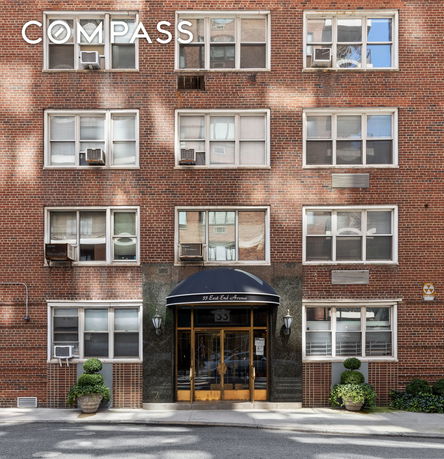 Front view of a brick apartment building with multiple windows and a central entrance.