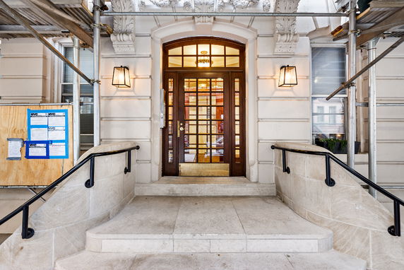Front view of a building entrance with arched door and stone steps.