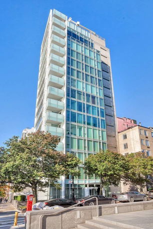 Front view of a tall glass building with multiple floors and balconies.