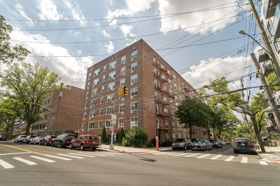 Front view of a multi-story brick apartment building on a street corner.