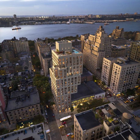 Panoramic view of a cityscape with a prominent high-rise building and a river in the background.