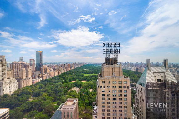 Panoramic view of a cityscape with a park, high-rise buildings, and a clear blue sky.