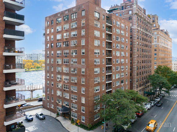 View of multiple brick apartment buildings near a street and river.