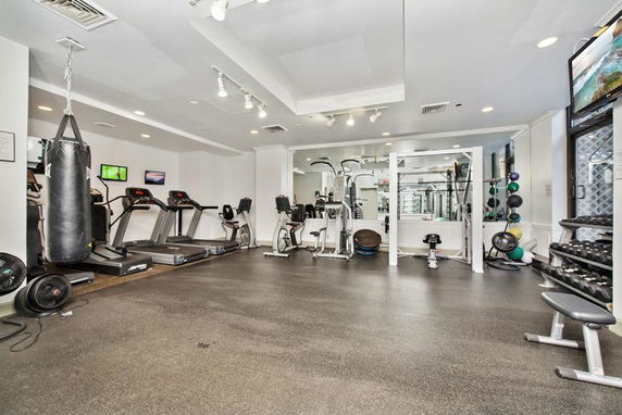 Indoor gym area with exercise equipment including treadmills and weights.