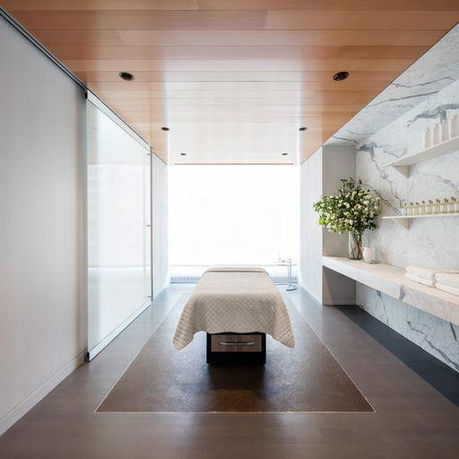 Interior view of a modern spa room with a massage bed and minimalist decor.