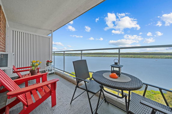 Balcony with seating overlooking a large body of water and landscape.