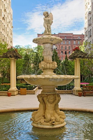 Ornate fountain with cherub statue in a courtyard between buildings.