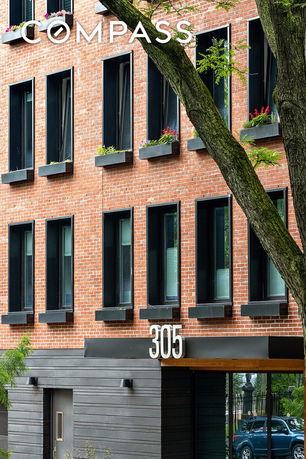 Front view of a brick apartment building with multiple windows and a prominent number 305.