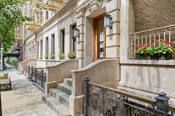 Front view of a building with ornate railings and potted flowers on windowsills.